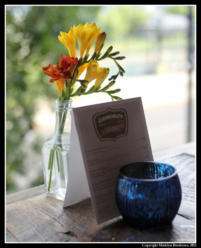 Stoneground's summer menu propped against a small vase of flowers.