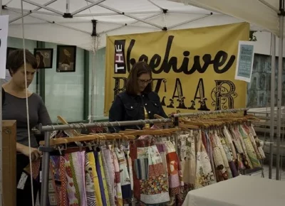Women browsing the clothing rack at the Beehive Bazaar booth.