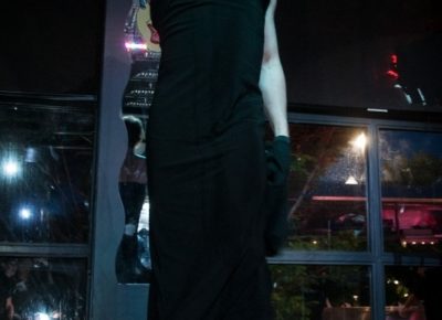 Sophia Scott wearing a black dress and black gloves
