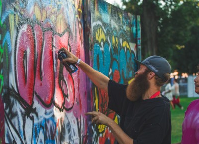 Benny from Uprock shows an interested tagger some line work as they decorate a wall with their art.
