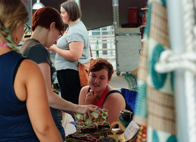 Crys Lee goes over fabric swatches at her booth, Amaa. Customers pick their fabric and Lee sources the custom dresses from artists in Ghana. Photo: @snowlenda