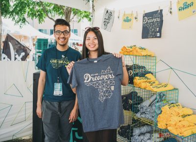 (L–R) Craft Lake City Merch Coordinator Francisco Ortega and SLUG Editorial Assistant Kathy Zhou look at shirts in the Craft Lake City merch booth. Photo: @clancycoop