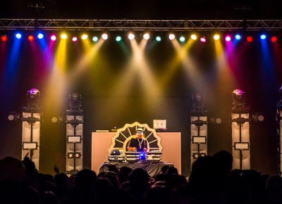 DJ Whooligan mixes underneath a variety of colored spotlights.
