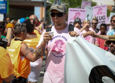 SLUG writer Jeremy Cardenas accepts water from Pride volunteers as the march begins. The Pride Parade route temperature quickly rose into the high 90s. Photo: John Barkiple