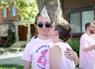 (L–R) Christian Fox earns a kiss from SLUG Magazine’s Mel Wise after marching with SLUG in the pride parade. Wise is an issue designer who builds whole page designs and typesets copy. Photo: John Barkiple