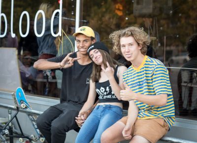 (L–R) Adrian Evans, Madeline Schierbaum and Jake Knaphus hold to the iron rail in front of Gold Blood’s new storefront. Knaphus described Evans, who sometimes rides for 5050, as the instigator behind many of Salt Lake’s community-related BMX events. Photo: John Barkiple