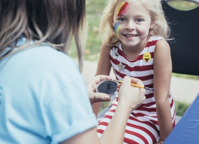 An excited girl halfway through her Pink Floyd Dark Side of the Moon face painting. Photo: @william.h.cannon