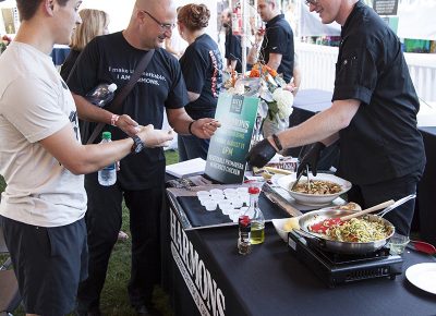 A Harmons Cooking School instructor divvies out samples of vegetable primavera with herbed chicken, made during a craft food demo, to the patrons in the VIP area. Photo: @jbunds