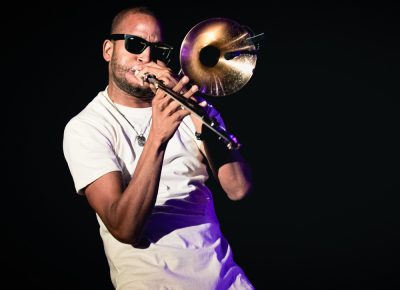 Trombone Shorty stepping out of the main stage lights and closer to the audience in the shadows. Photo: Lmsorenson.net
