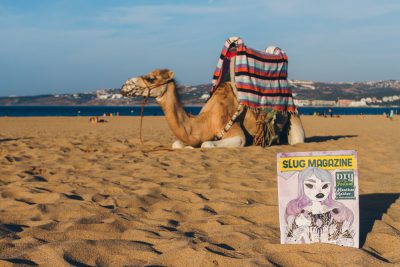 SLUG Mag catching some rays out on the beach of Tangier next to a Moroccan camel. Photo: Talyn Sherer
