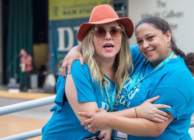 (L-R) Craft Lake City Entertainment Coordinator Kellie Call and Production Volunteer Danielle Turner embrace on the Gallivan Plaza bridge. Call split her time between the SLUG stage and the KRCL stage as she checked on DIY Festival performers.