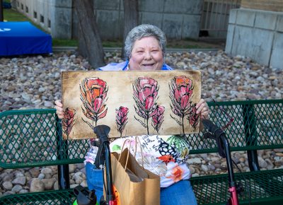 Paula Miller holds a painting purchased by her daughter. “If she sees something she likes, she has to have it,” Miller said.