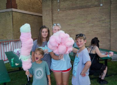 Kids posing with their collection of cotton candy in the Harmons VIP Area.