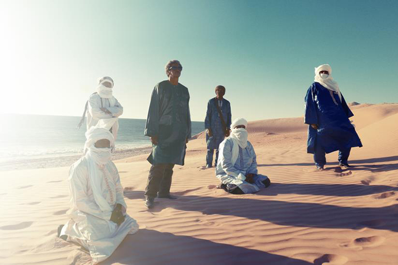 Members of Tinariwen cast shadows upon the desert.