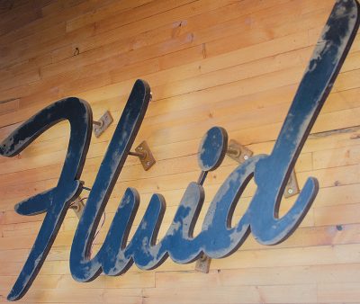 Fluid's rustic logo mounted on their wood walls. 