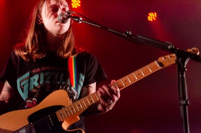 Julien Baker basking in red lights during her performance at The Complex.