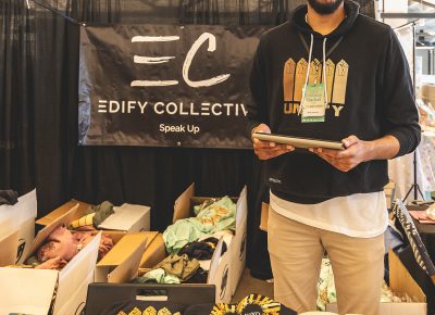 Edify Collective vendor enjoying the event while vending some rad merch.