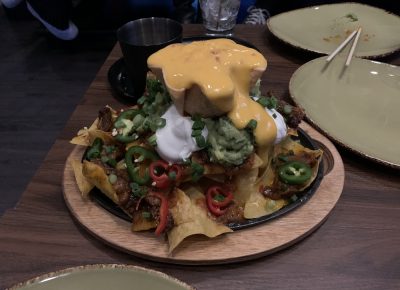 Flankers Smoked Brisket Nachos feature Texas-style BBQ brisket, a melted, three-cheese blend, guacamole, sour cream, roasted tomato salsa and a pour over of cheese to top it off.