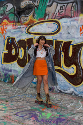 Cintia Lastra on roller skates in front of a wall of graffiti.