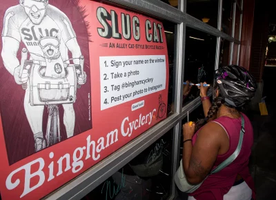 SLUG Cat participant signs Bingham Cyclery window.