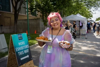 DIY Fest attendee smiles while holding chicken and beignets.