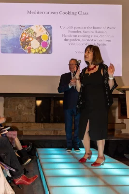 L–R With auctioneer Larry Flynn in the background, Women of the World founder Samira Harnish promotes her Mediterranean Cooking Class for up to 10 guests. Photo: John Barkiple