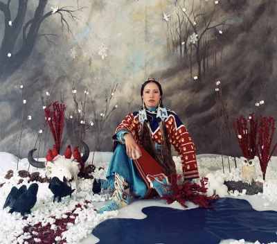 An Indigenous woman sits posed in front of winter photoshoot backdrop. Photo courtesy of UMFA. 