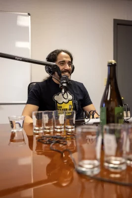 David Jimenez smiles at a table during a recording of Tastemasters. Several glasses and a beer bottle foreground him. Photo: John Barkiple