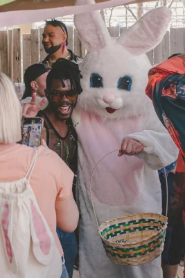 Person poses with the easter bunny. The Easter Bunny is holding an Easter basket.
