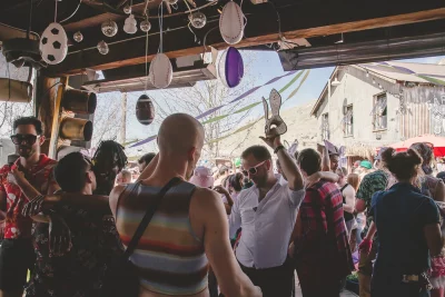 A picture of a group of people dancing in a covered outdoor area. There are pink easter eggs hanging from the ceiling.