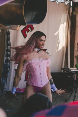 Image shows special quest BoyaBADDIE mid-performance. They are wearing a pink corset and bowtie.