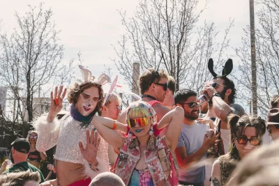 Group of attendees dancing. The one in the middle is wearing a pink, patch-covered vest and Pit Vipers.