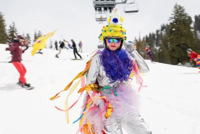 A person looks into the camera, adorned in a tutu, boas and colorful streamers. Photo: Jovvany Villalobos