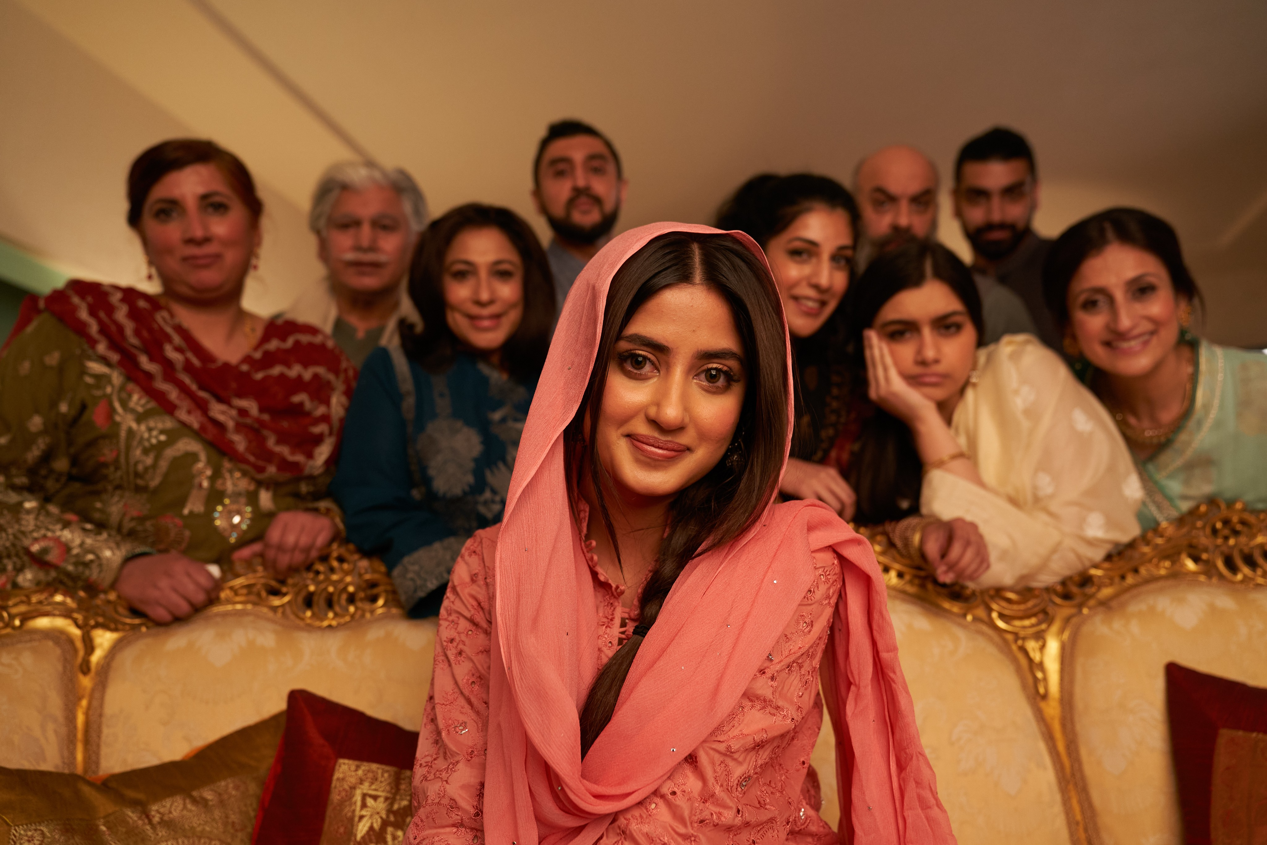 A young girl sits surrounded by others.