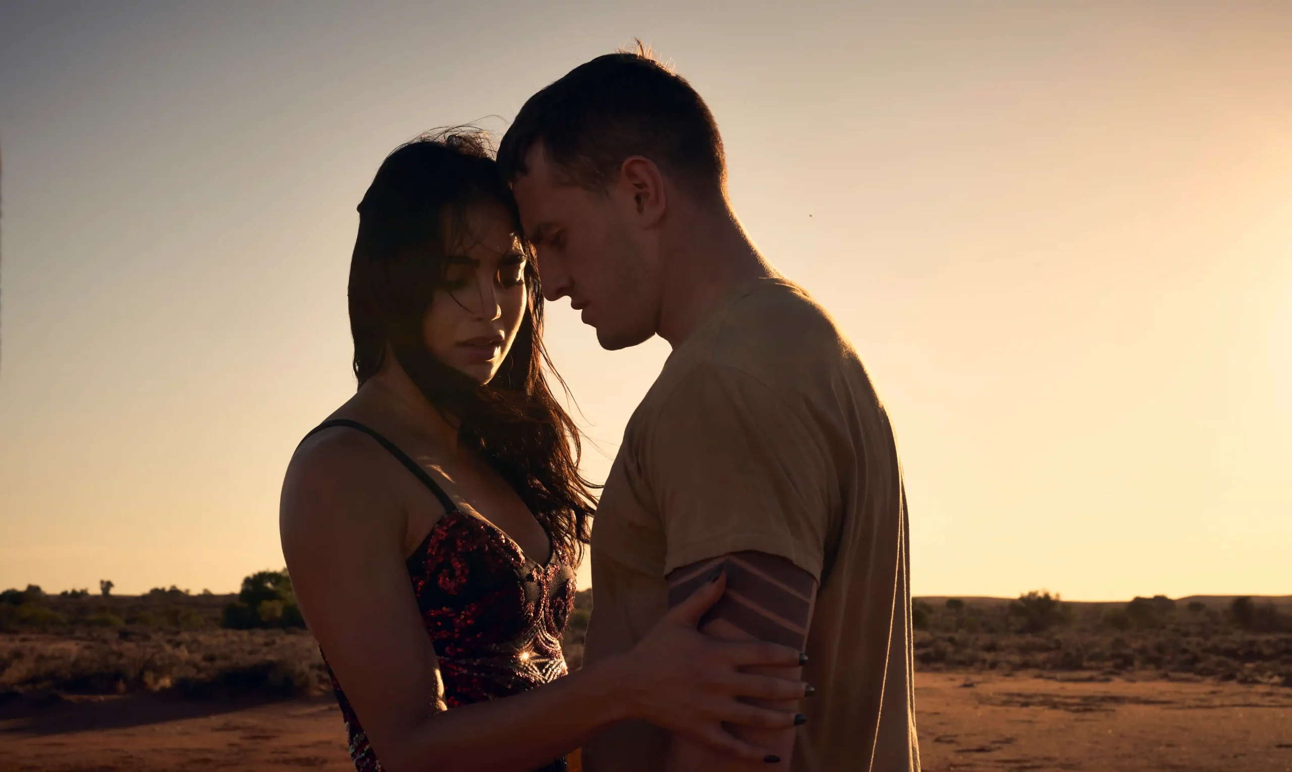 The two leads of Carmen stand close to one another in a desert environment.