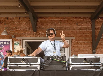 A dj giving a peace sign while playing music.