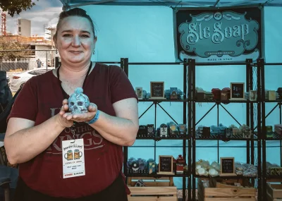 Worker holding up a skull shaped soap at the SLC Soaps booth.
