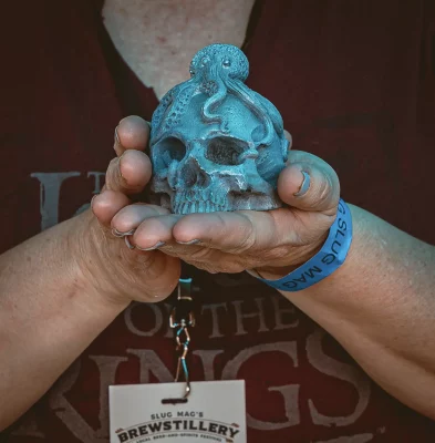A close up picture of hands holding a blue skull-shaped soap.