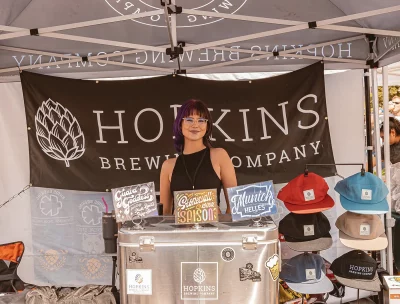Picture of a person working the Hopkins Brewing booth.
