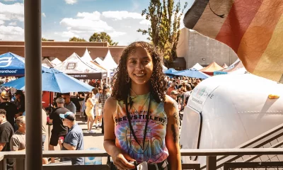 Hunter Weston in a tie-dye t-shirt. Behind her is a group of tents and a crowd of people.