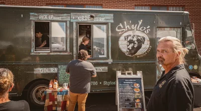 A person paying for food outside of a food truck.