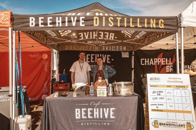Two people working the Beehive Distillery tent.