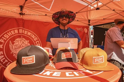 Fischer Brewing worker smiling with Fischer Brewing themed hats.