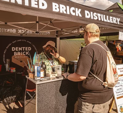 The Dented Brick Distillery tent making a cocktail for a customer.
