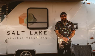 A person posing in front of a large white van with the words "Visit Salt Lake" on it.