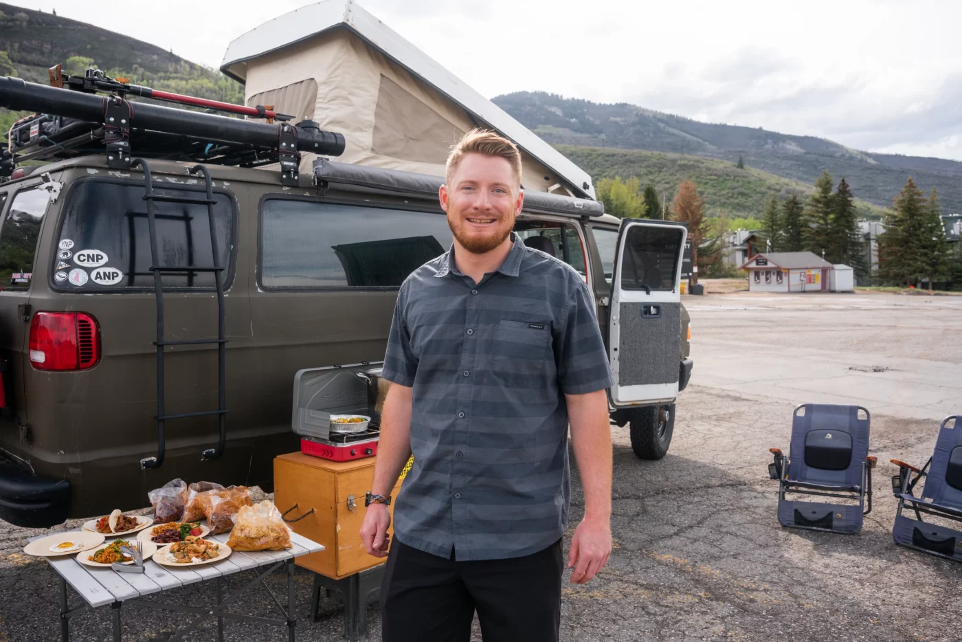 John Fitzgerald stands in front of his truck, next to a table of cooked food.