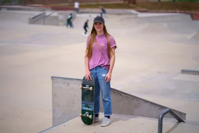 Cassidy Andersen stands with a skateboard at the top of a ramp.
