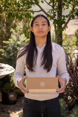 Krado poses outside with their product, leaflet™, in a cardboard box. 