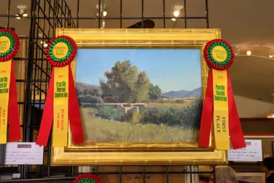 The framed painting by Brad Aldrich is displayed with a first place ribbon. 