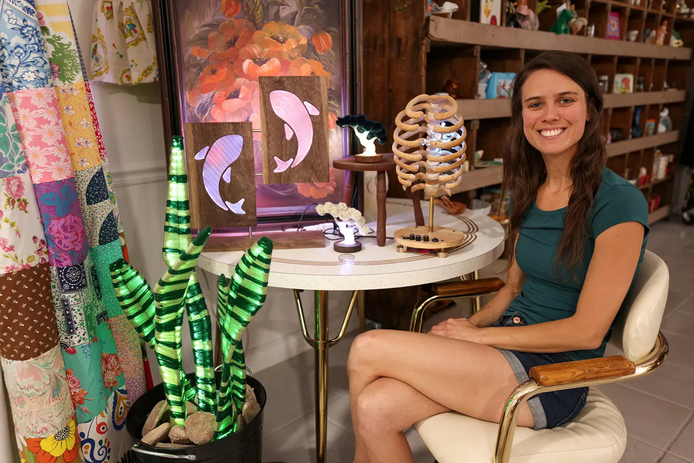Michelle Sharer sits next to a few of her creations, including colorful sculptures on seaweed, koi fish and a ribcage.